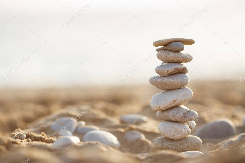 sea stones tower on sand. summer and sunset on sea background. relaxation and meditation on beach. High quality photo