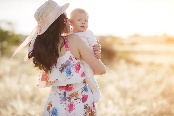 Mother feeding her newborn baby boy from bottle outdoors in the field. artifitial milk feedng — Stock Photo, Image