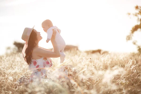 Moeder voeden van haar pasgeboren baby jongen uit fles buiten in het veld. kunstmatig melkvoeder — Stockfoto