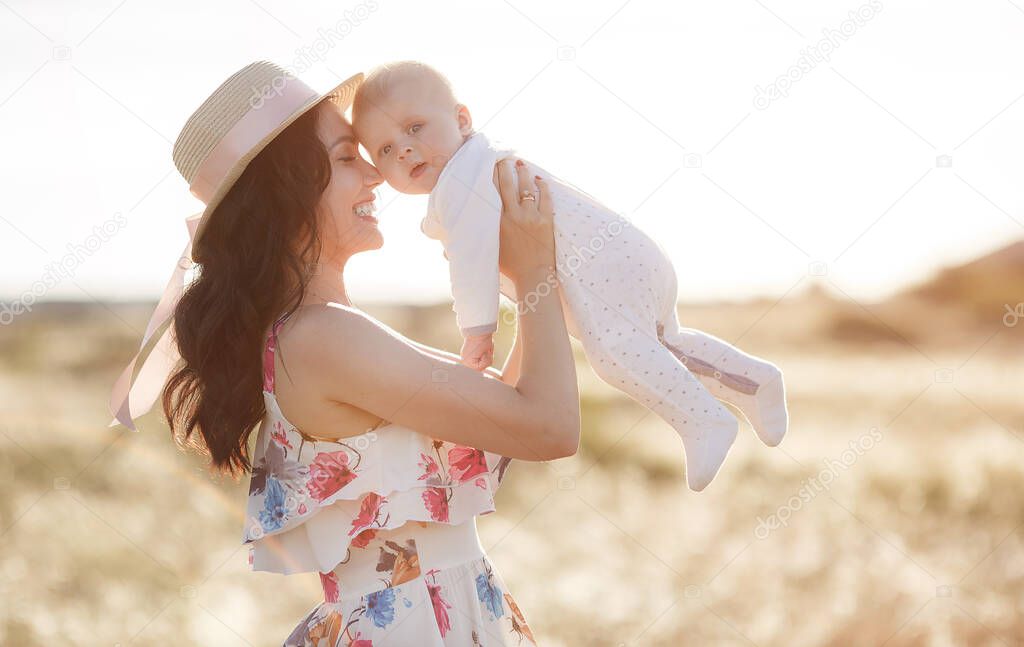 mother feeding her newborn baby boy from bottle outdoors in the field. artifitial milk feedng