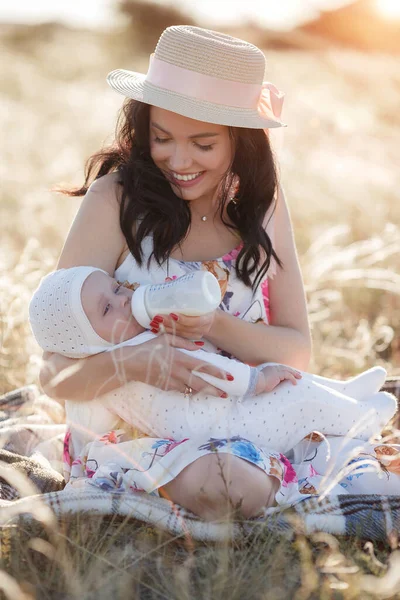 Mutter füttert ihr Neugeborenes aus Flasche im Freien auf dem Feld künstliche Milchfütterung — Stockfoto