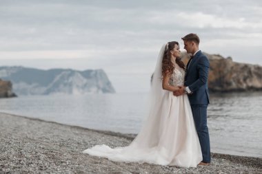 Deniz ve dağ kenarında güzel bir yerde düğün çifti, gelin ve damat sahilde.