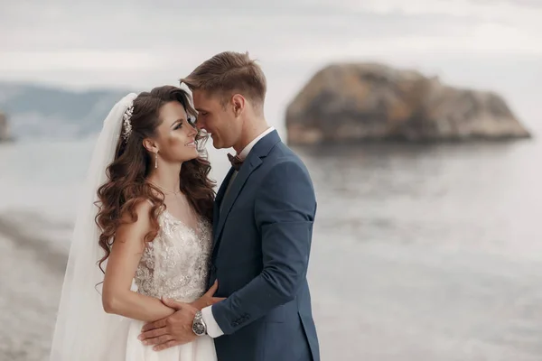 Wedding couple in a beautiful place by sea and mountains, Bride and groom on beach — Stock Photo, Image