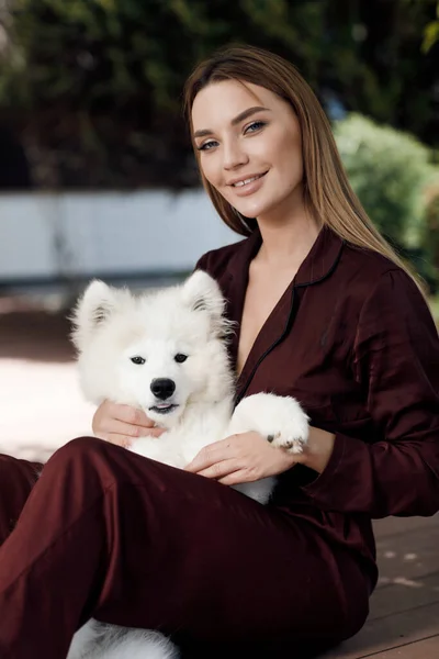 Joven mujer sonriente sentada con perro al aire libre —  Fotos de Stock