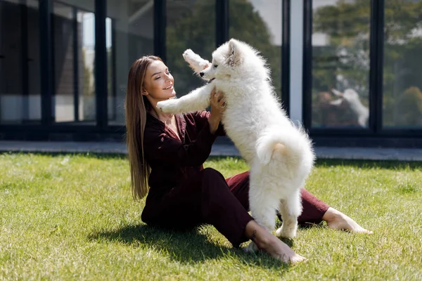 Joven mujer sonriente con perro al aire libre cerca de casa — Foto de Stock