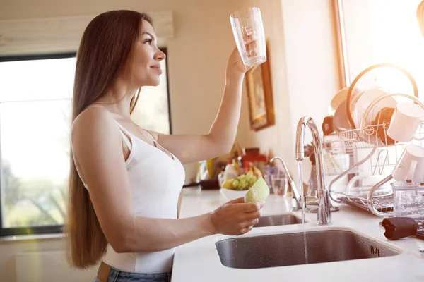 Güzel kadın evde temizlik yapıyor ve bulaşıkları yıkıyor. — Stok fotoğraf