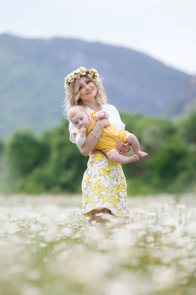 Mujer feliz con el niño pequeño en camomilles. campo blanco floreciente. familia en flores. madre e hijo —  Fotos de Stock