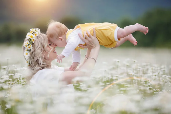 Happy woman with little baby boy in camomilles. blooming white field. family in flowers. mother and son — Stock Photo, Image