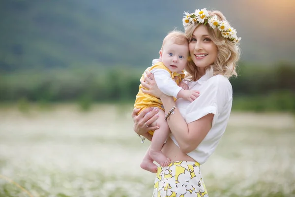 Mujer feliz con el niño pequeño en camomilles. campo blanco floreciente. familia en flores. madre e hijo —  Fotos de Stock