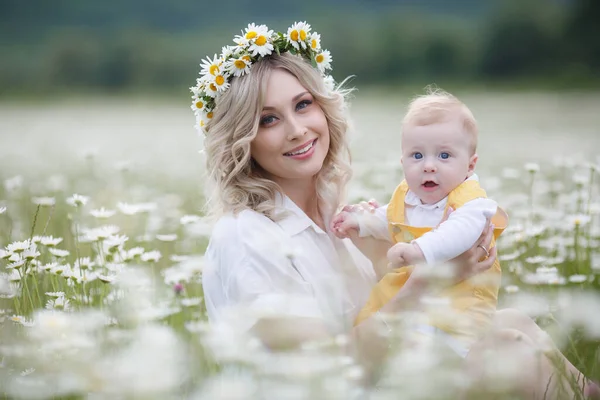 Boldog nő kisfiúval Camomilles-ben. Virágzó fehér mező. Család virágokkal. Anya és fia. — Stock Fotó