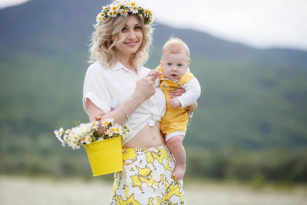 Gelukkige vrouw met kleine baby jongen in camomilles. Bloeiend wit veld. familie in bloemen. moeder en zoon — Stockfoto