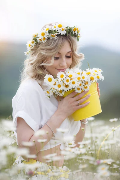 Bonita mujer rubia joven con manzanillas en el campo de floración blanca. chica en corona de manzanilla —  Fotos de Stock