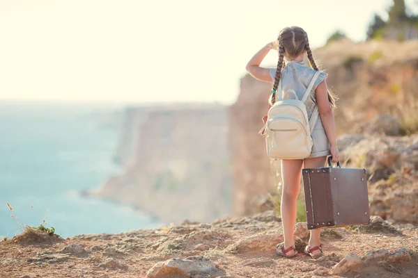 Viaggiatrice bambina. viaggio da solo. ragazza che cammina con macchina fotografica e valigia sulla natura via mare. viaggi, vacanze, vacanze — Foto Stock