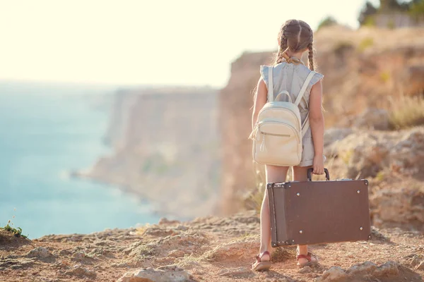 Çocuk gezgin. Yolculuk yalnız. Kamera ve bavulla deniz kenarında yürüyen bir kız. seyahat, tatil, tatil — Stok fotoğraf