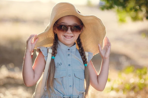 Mooi klein meisje in gestreepte jurk en hoed ontspannen op het strand in de buurt van zee, zomer, schattig klein meisje op strand vakantie — Stockfoto