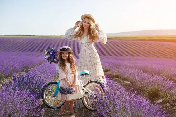 Hübsche Mutter mit Tochter beim Spielen im Lavendelfeld. Frau mit Kind im Sonnenuntergang beim Sammeln von Lavendelblumen — Stockfoto