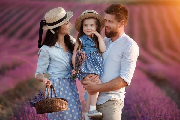 Familia feliz en el campo de laveder. madre, padre e hijo en la luz del atardecer en flor lavanda — Foto de Stock