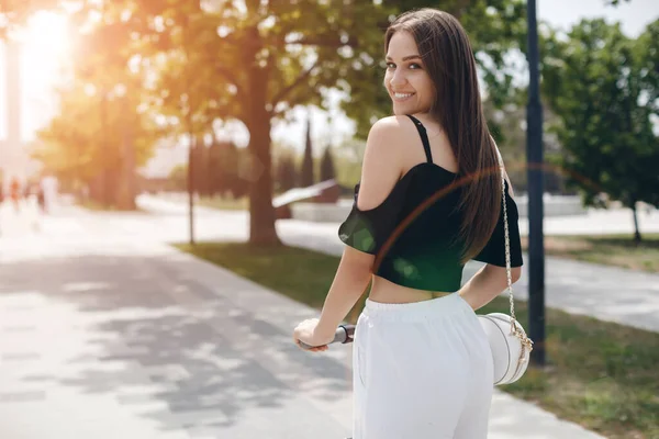 Young woman at electric scooter in the park — Stock Photo, Image