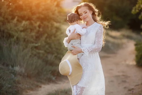 Belle jolie femme avec bébé garçon au coucher du soleil à l'extérieur. mère avec fils — Photo