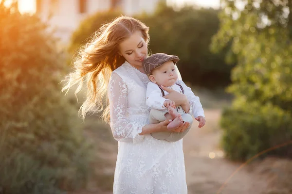 Mulher bonita bonita com menino no pôr do sol ao ar livre. mãe com filho — Fotografia de Stock