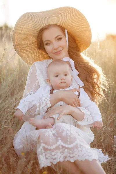 Belle jolie femme avec bébé garçon au coucher du soleil à l'extérieur. mère avec fils — Photo