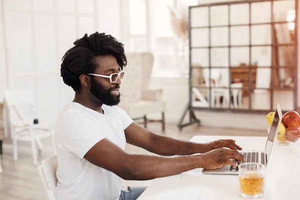 Giovane uomo nero che lavora a casa con il computer portatile — Foto Stock