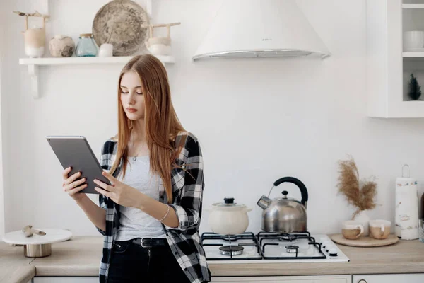 Giovane donna guardando tablet a casa sua cucina — Foto Stock