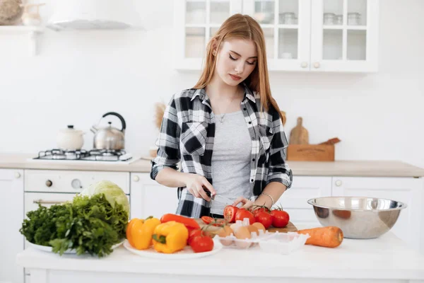 Mujer joven cocinando en casa en la cocina con tabletas en tapones para los oídos — Foto de Stock