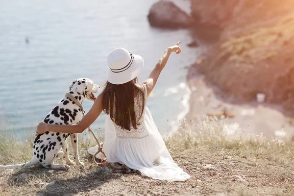 Женщина с собакой далматинкой. Девушка и ее подруга собака на синем морском фоне — стоковое фото
