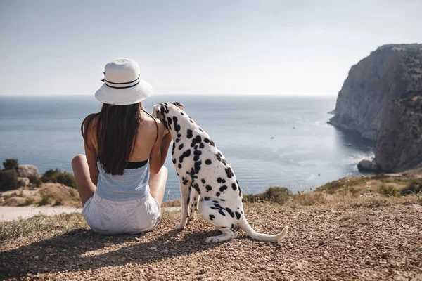 Kvinna med en hund dalmatier. tillbaka sitta flicka och hennes vän hund på blå havet bakgrund — Stockfoto