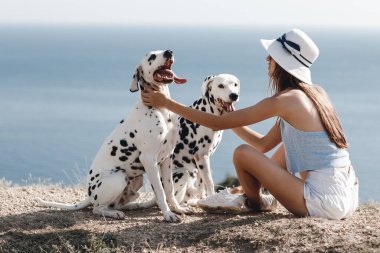 Genç bir kadın mavi arka plan suyunda köpeğini dalmaçyalıları eğitiyor.