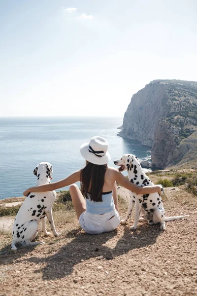 後ろ側に座っている女性とともに犬ダルマチアの屋外近くに青い海 — ストック写真