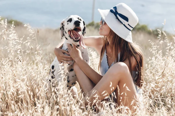 Kvinna med en hund dalmatian i ett fält på sommaren — Stockfoto