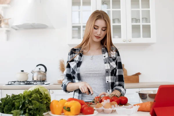 Молодая женщина готовит дома на кухне с планшетом — стоковое фото