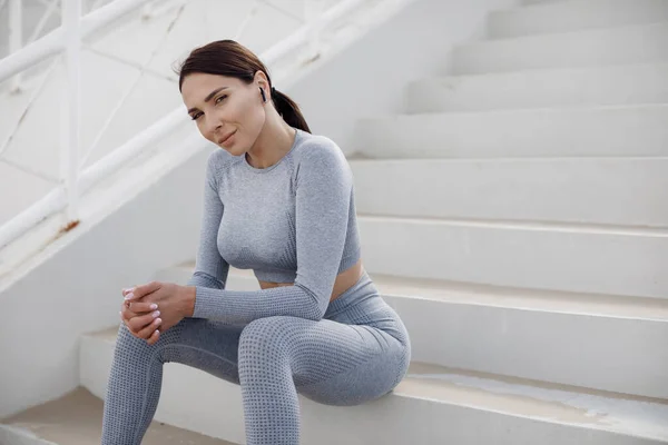 Retrato de fitness mujer al aire libre sentado en las escaleras en el estadio —  Fotos de Stock