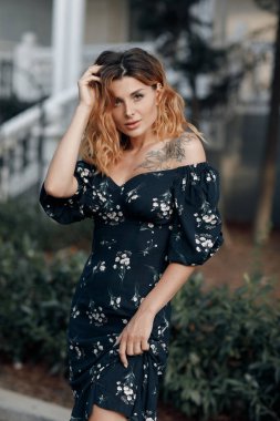 Gün batımında şehir caddesinde yürüyen mutlu genç bir kadın. Yazın açık havada gülümseyen duygusal kız