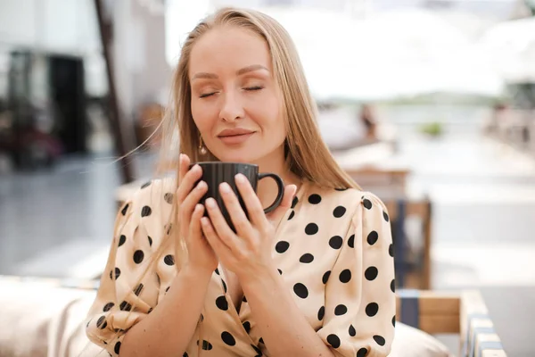 在咖啡厅阳台上的年轻而随意的女人，一杯咖啡，沉着而快乐 — 图库照片