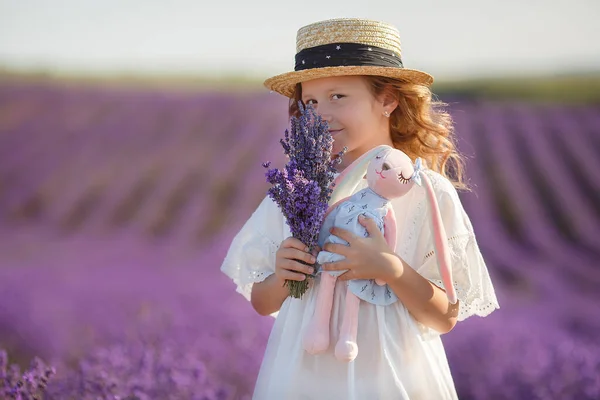 Söt preteen flicka i vit klänning och hatt har kul i blommande lavendel fält. Porträtt i blommor — Stockfoto