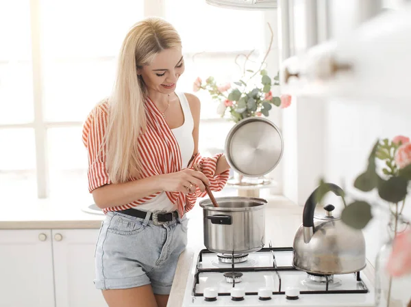 Beatiful sonriente mujer está cocinando en kichen en casa —  Fotos de Stock