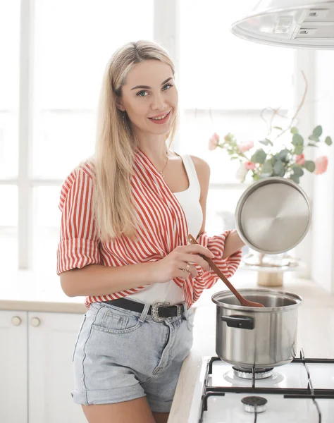 Mulher sorridente beatiful está cozinhando em kichen em casa — Fotografia de Stock