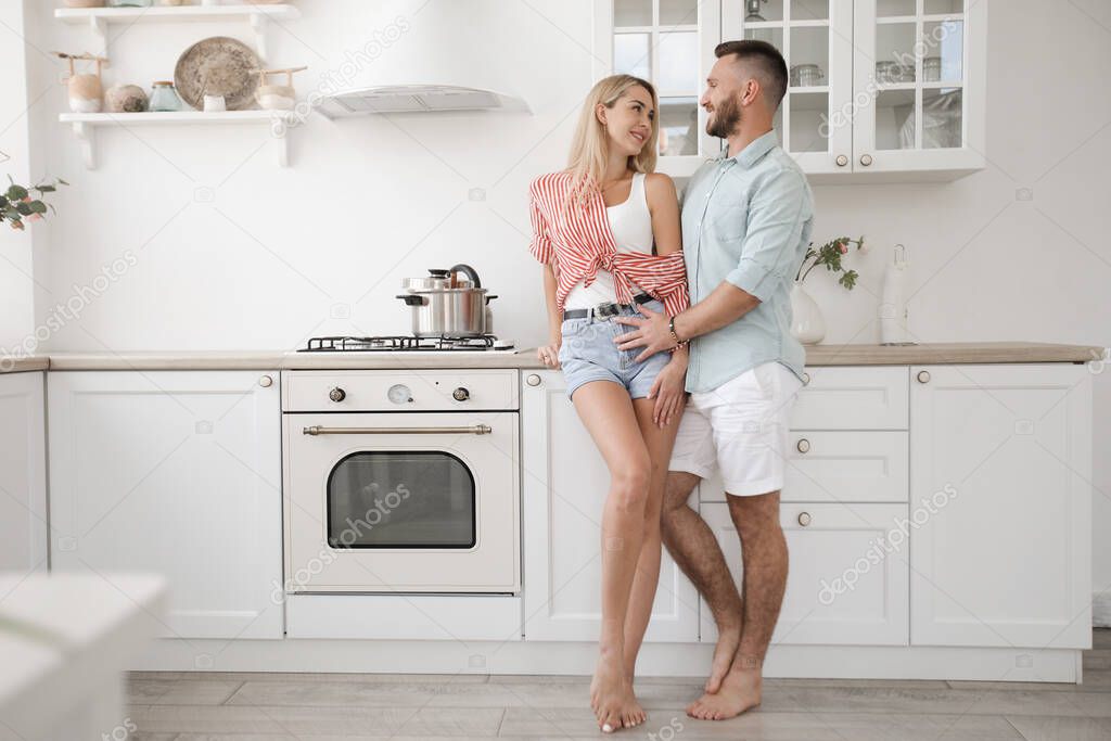 Handsome man and attractive young woman are having fun together in kitchen. Healthy lifestyle concept.