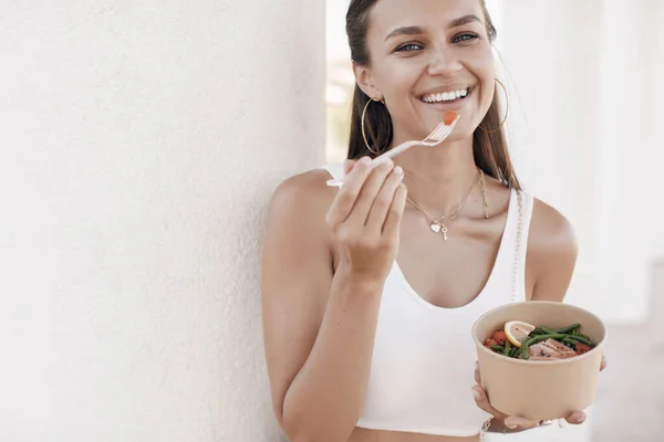 Primer plano retrato de una joven feliz hermosa mujer comiendo comida saludable en un tazón en la calle — Foto de Stock