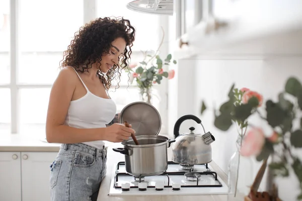 Mooie vrouw koken soep thuis in keuken — Stockfoto