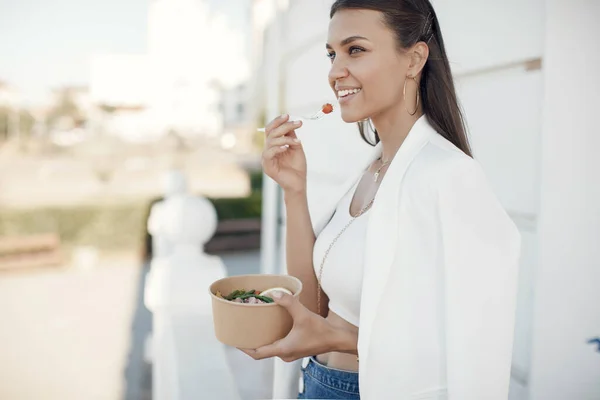 Feliz joven hermosa mujer comiendo comida fresca en un tazón en la calle — Foto de Stock