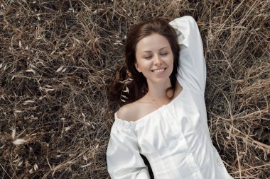 Bir kadın yaz günü kuru çimlerde eğleniyor. Mutlu kız portresi