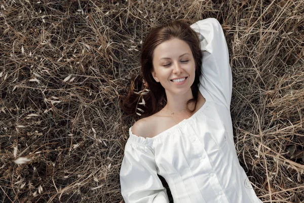 Bir kadın yaz günü kuru çimlerde eğleniyor. Mutlu kız portresi