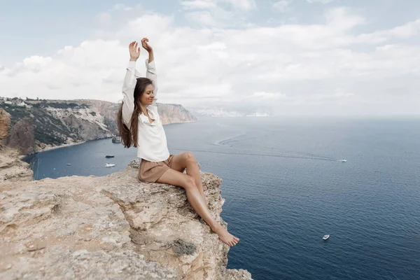 美丽的女人在山上的边缘在大海和天空的背景。夏天的天性美丽的肖像 — 图库照片