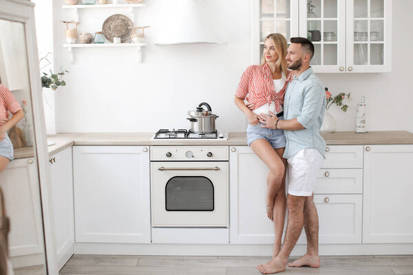 Handsome man and attractive young woman are having fun together in kitchen. Healthy lifestyle concept.