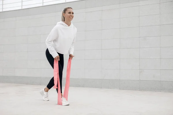 Retrato de la mujer joven en forma y deportivo haciendo estiramiento en la ciudad al aire libre —  Fotos de Stock