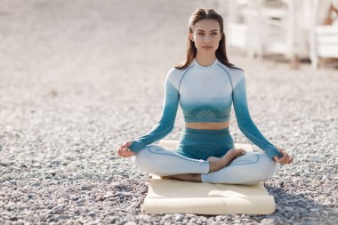 Kafkasyalı genç kadın deniz kıyısında yoga yapıyor.